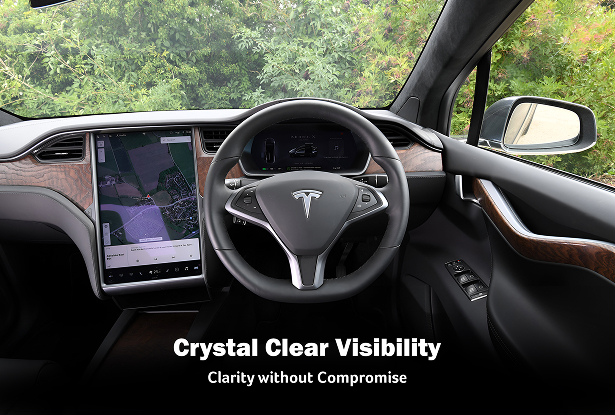 Interior view of a Tesla vehicle showcasing the steering wheel with the Tesla logo, a large central touchscreen displaying a map, and a digital dashboard. The windshield offers a clear view of greenery outside, with overlaid text reading “Crystal Clear Visibility” and “Clarity without Compromise.”