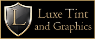Logo for Luxe Tint and Graphics featuring a silver and gold shield with a prominent letter "L" on it, alongside elegant serif text reading “Luxe Tint and Graphics” on a black background with gold trim.