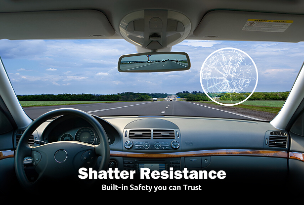 View from inside a car driving on an open highway, showing the dashboard, steering wheel, and windshield. A circular highlight on the passenger side of the windshield displays a cracked but intact glass area, with overlaid text reading “Shatter Resistance – Built-in Safety you can Trust.”