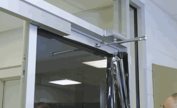 Installer applying dark commercial window tinting film to a glass door for privacy and UV protection.